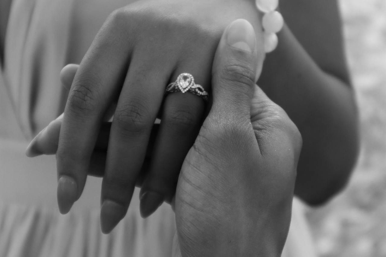 A black and white photo of a woman’s hand wearing a pear shape engagement ring