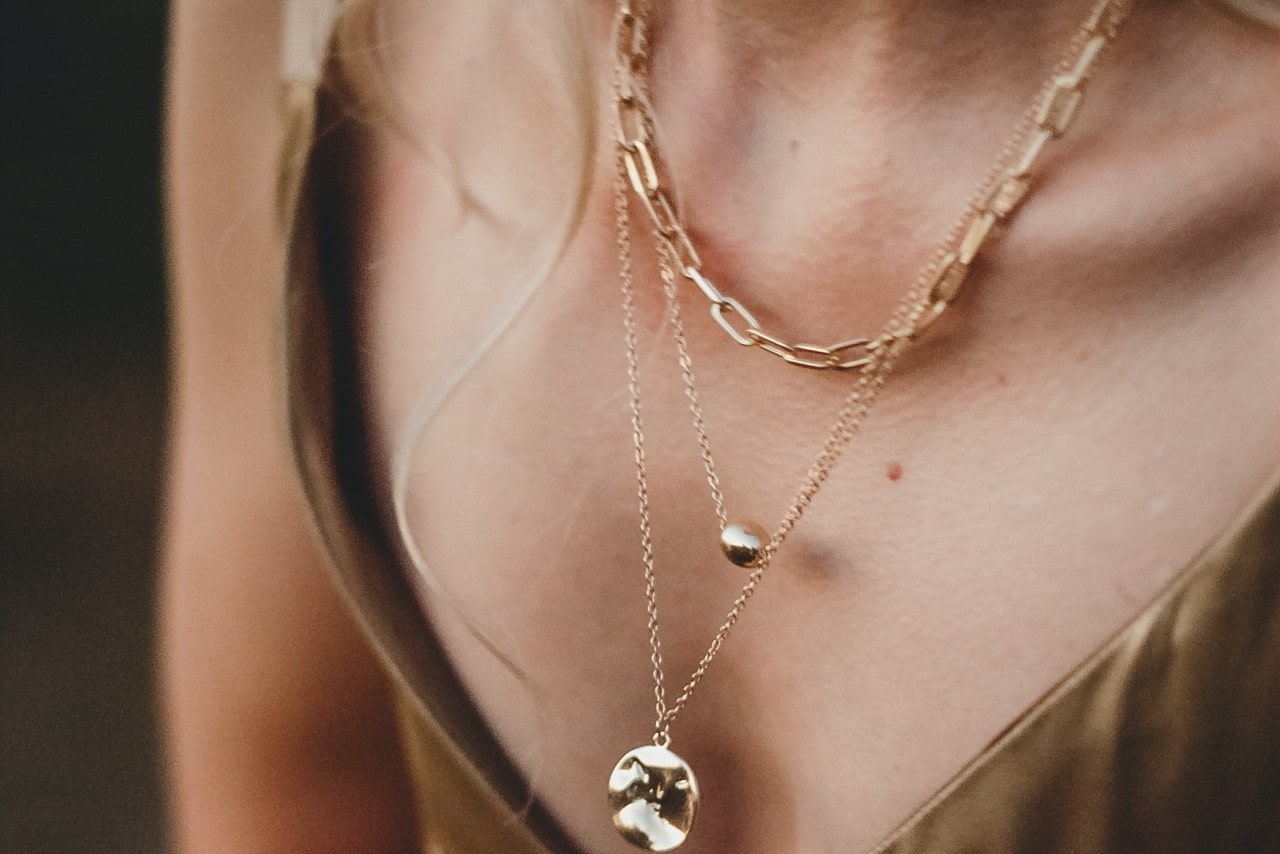 A large citrine gemstone on a gold chain with two other complimentary old necklaces