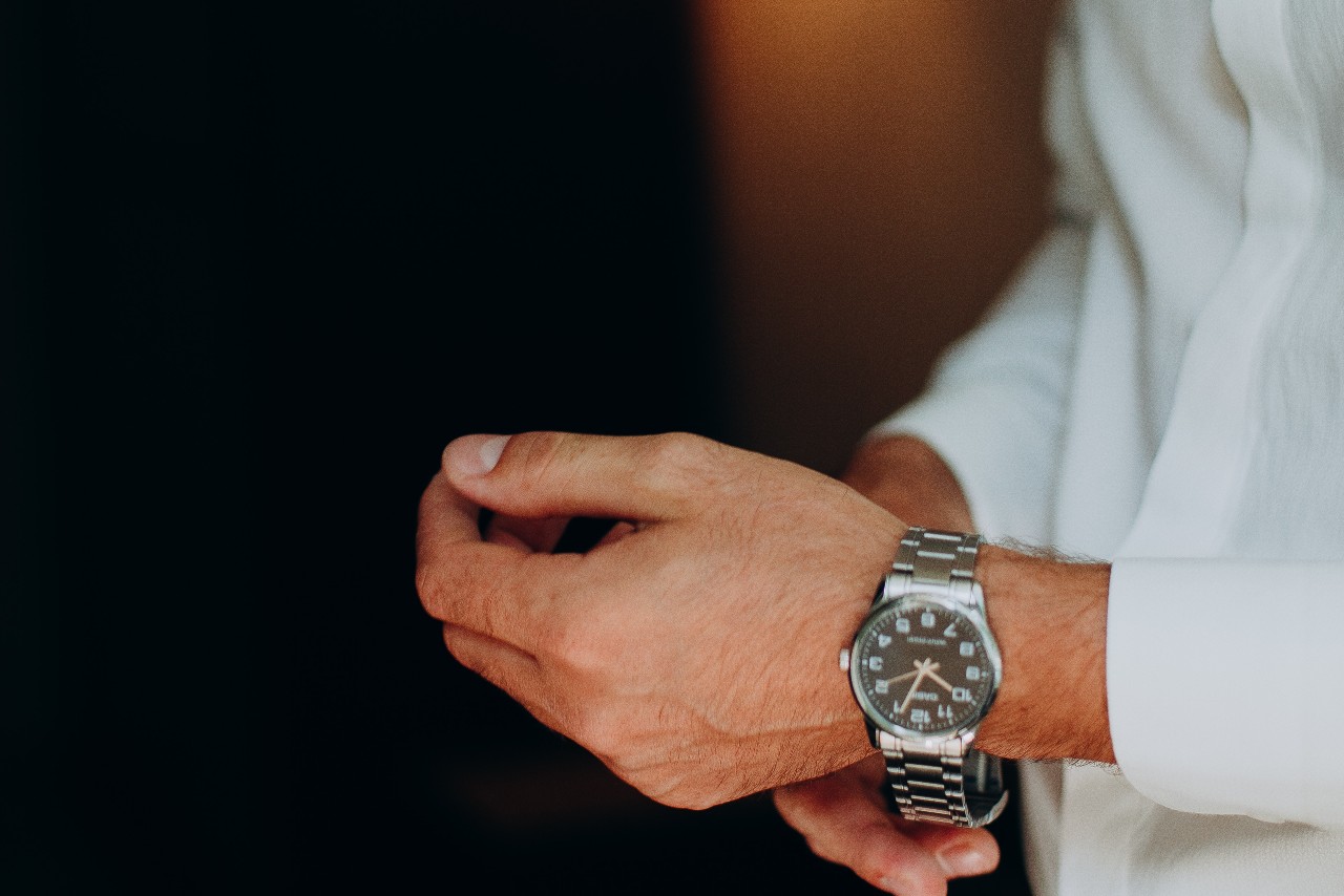 Man adjusting his watch and wearing a white button-up shirt