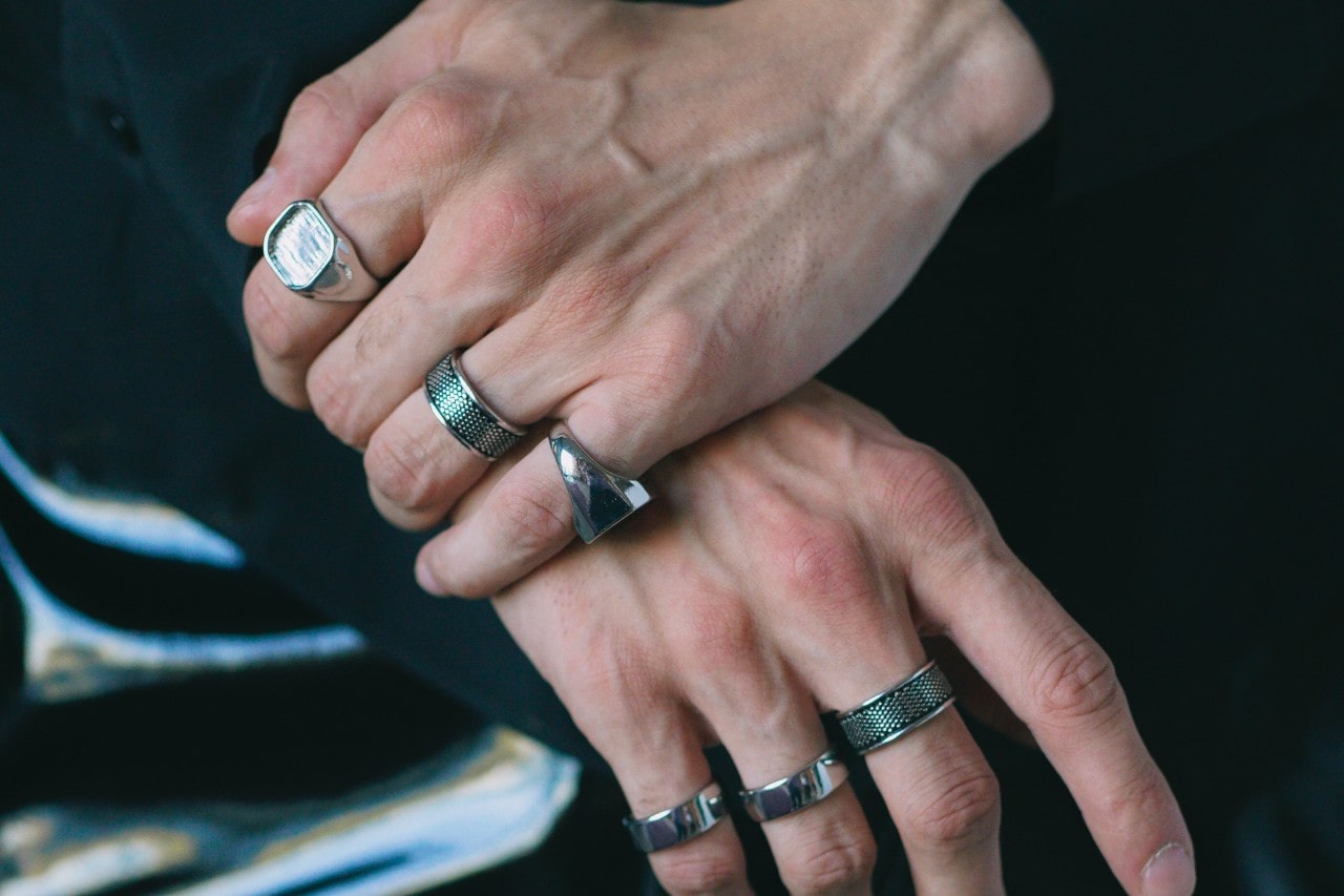 Man’s hands wearing a stack of silver rings on both hands