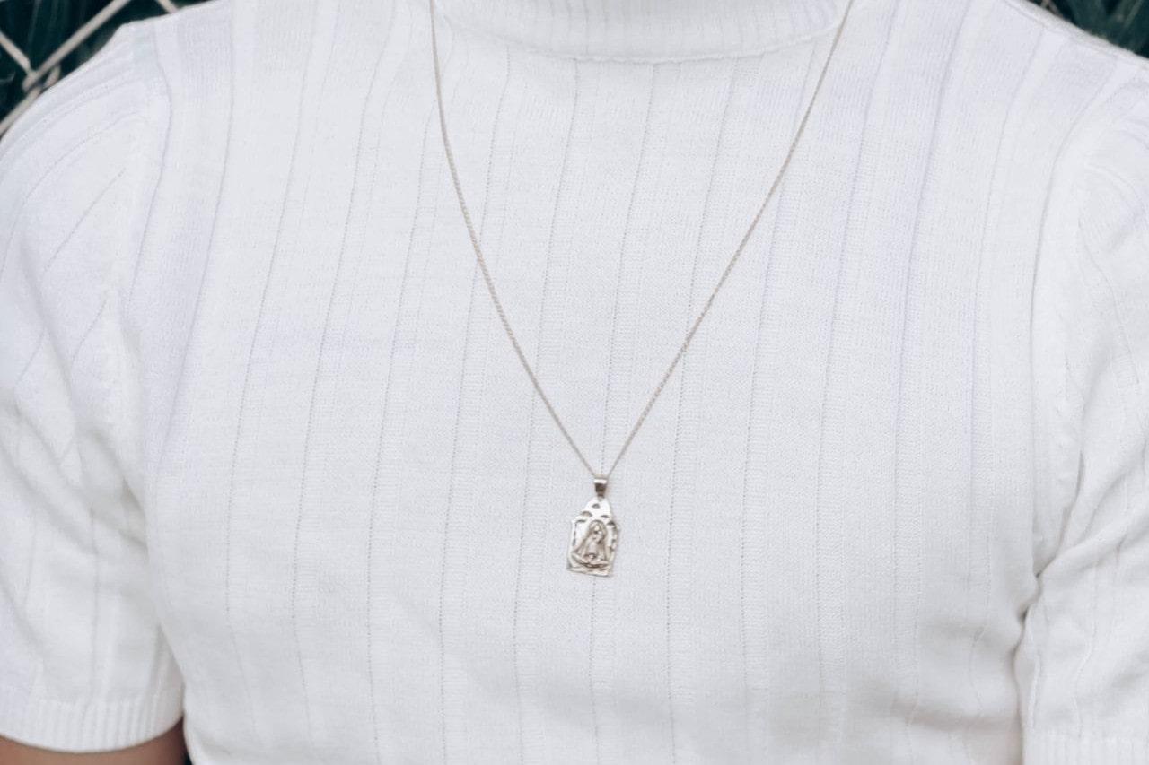 Close-up image of a man wearing a white shirt and silver pendant necklace