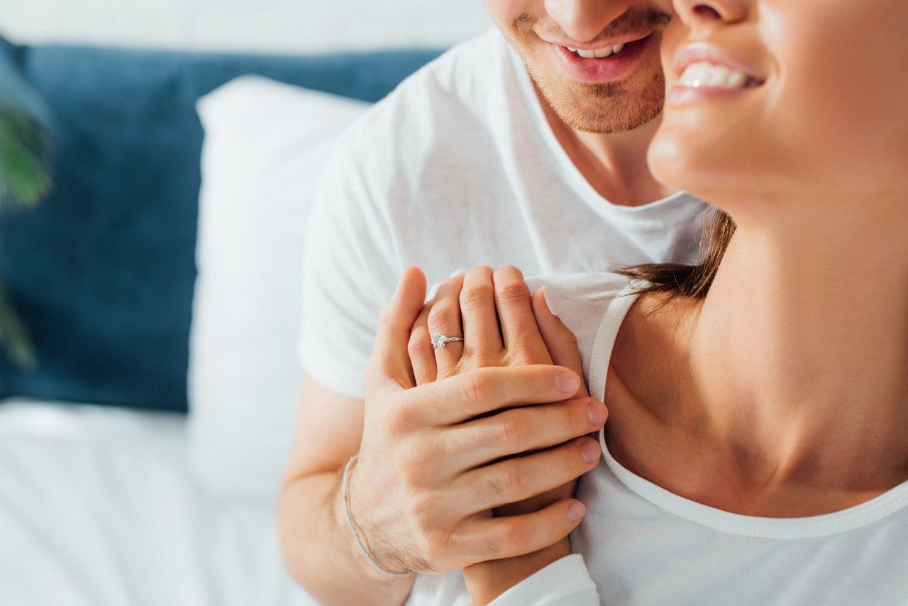 A man and woman embrace on a bed