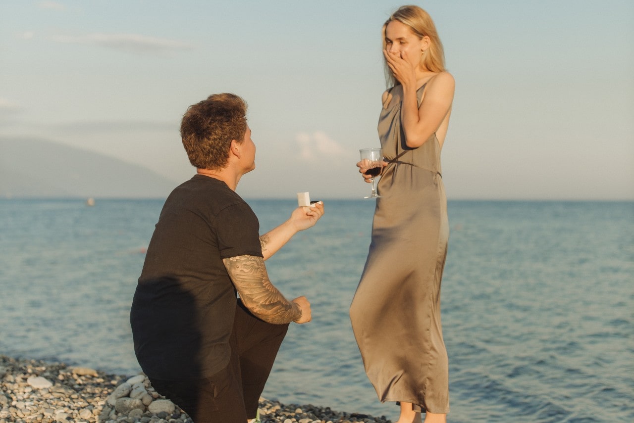 A man proposes to his girlfriend on a beach at sunset